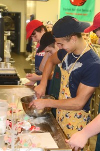 I chose this picture because we see all the guys smiling while mixing the dough and we see the mess of the workspace on the table. 